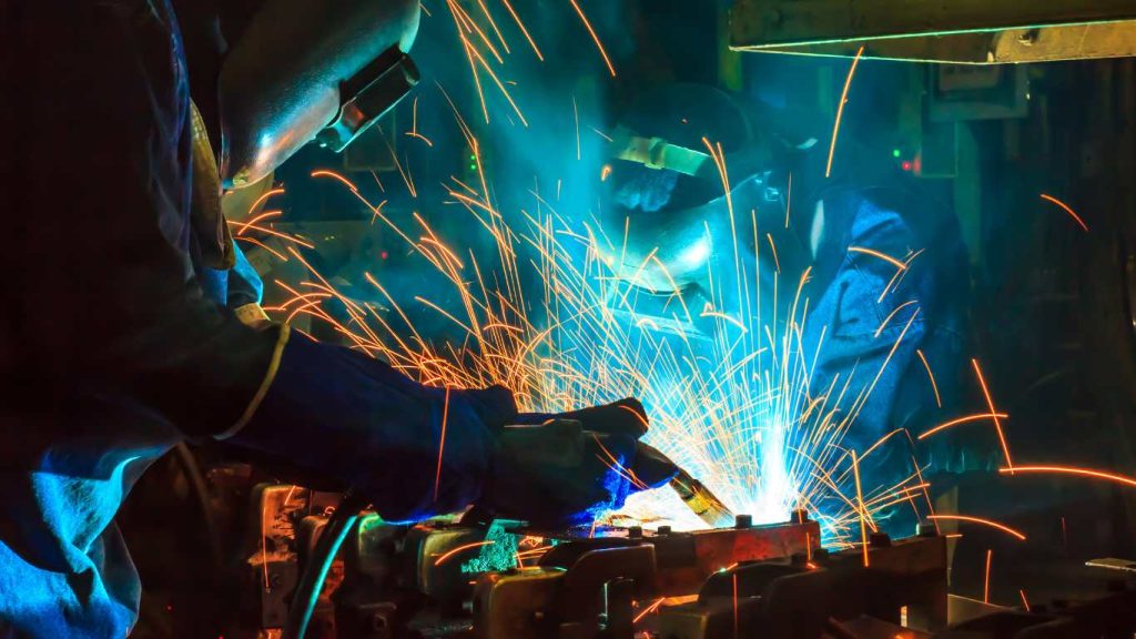 two men working on coded welding service with sparks